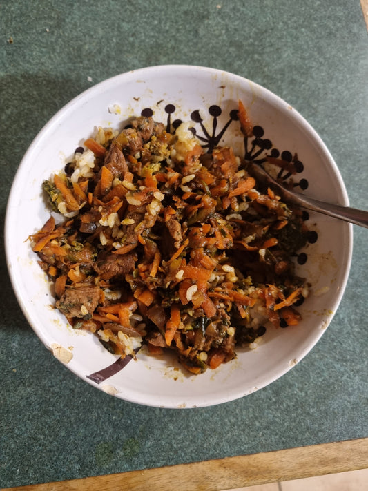Bowl of crunchy chilli honey lamb stir-fry with shredded carrots and broccoli served over steamed white rice.
