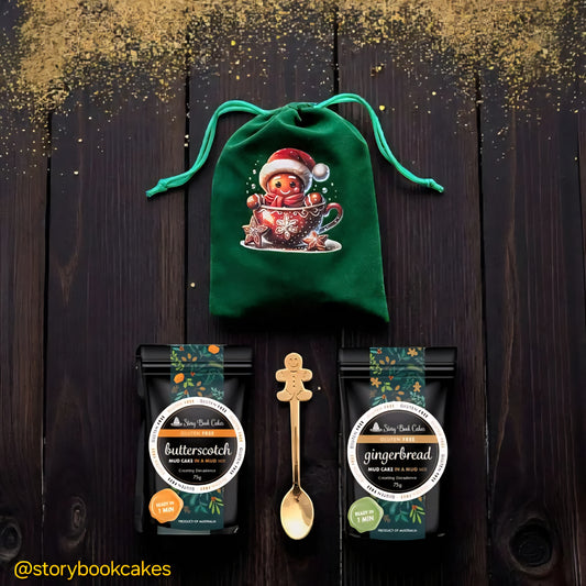 Green drawstring bag with a gingerbread man design, two cake mixes labelled 'Butterscotch' and 'Gingerbread', and a gold spoon on a dark background.